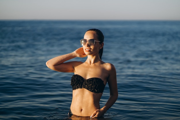 Mujer bonita morena relajante en la playa en el mar.