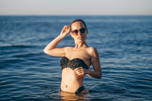 Mujer bonita morena relajante en la playa en el mar.