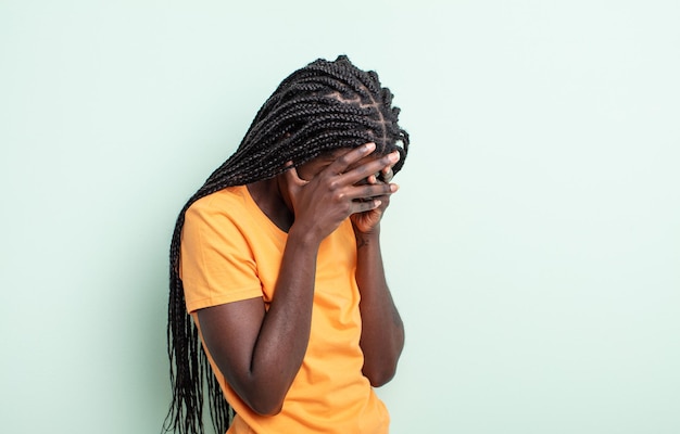 Mujer bonita negra que cubre los ojos con las manos con una mirada triste y frustrada de desesperación, llanto, vista lateral