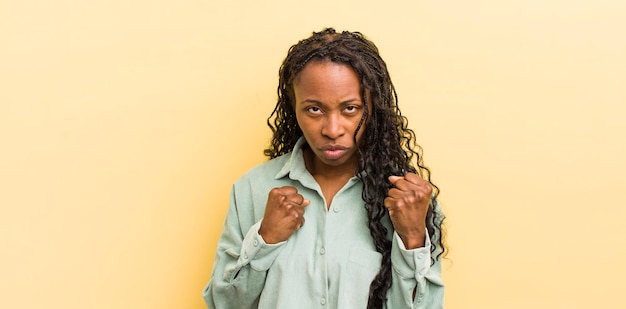 Mujer bonita negra que parece confiada, enojada, fuerte y agresiva con los puños listos para pelear en posición de boxeo