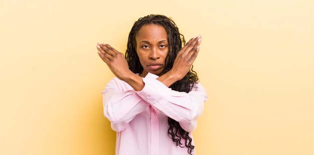 Mujer bonita negra que parece molesta y harta de tu actitud diciendo basta de manos cruzadas al frente diciéndote que te detengas