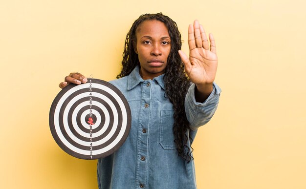 Mujer bonita negra que parece seria mostrando la palma abierta haciendo un gesto de parada