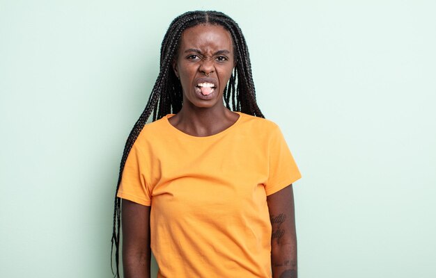 Mujer bonita negra que se siente disgustada e irritada sacando la lengua porque no le gusta algo desagradable y asqueroso