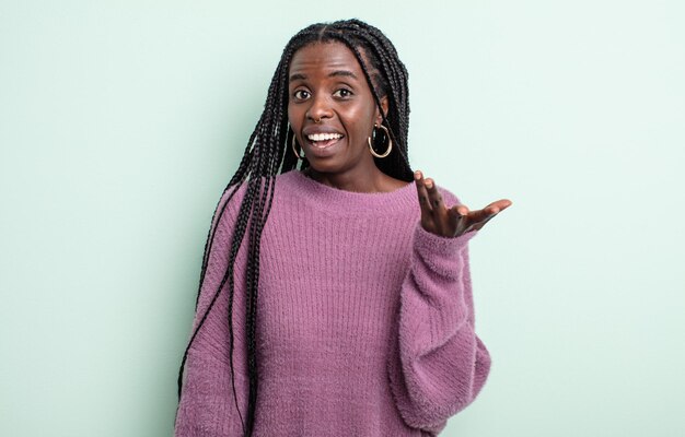 Mujer bonita negra que se siente feliz, sorprendida y alegre, sonriendo con actitud positiva, dándose cuenta de una solución o idea