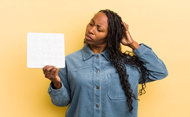 Foto mujer bonita negra que se siente perpleja y confundida rascándose la cabeza