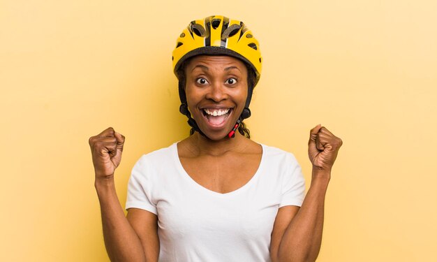 Mujer bonita negra que se siente sorprendida, riendo y celebrando el éxito