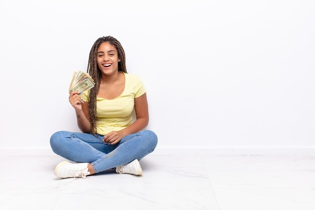 mujer bonita negra sentada en el suelo con facturas