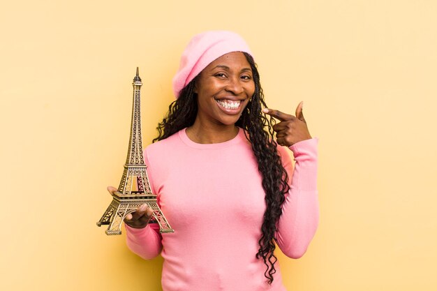 Mujer bonita negra sonriendo con confianza apuntando a su propia sonrisa amplia