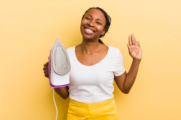 Mujer bonita negra sonriendo felizmente agitando la mano dándote la bienvenida y saludándote