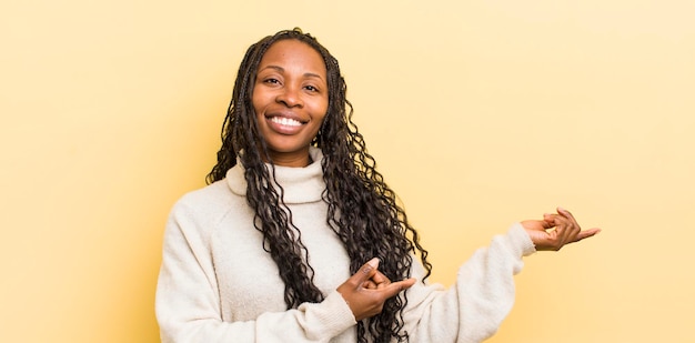 Mujer bonita negra sonriendo con orgullo y confianza sintiéndose feliz y satisfecha y mostrando un concepto en el espacio de la copia