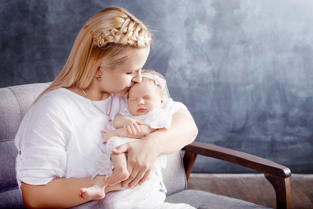 Mujer bonita con una niña recién nacida en sus brazos. Madre feliz y su bebé recién nacido deslizándose.