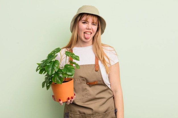 Mujer bonita pelirroja con actitud alegre y rebelde bromeando y sacando la lengua concepto de jardinero