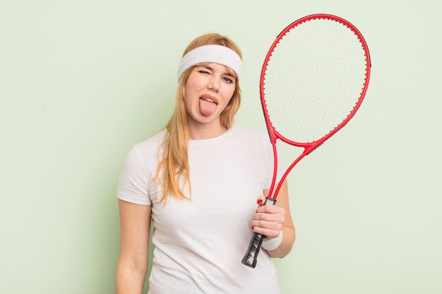 Mujer bonita pelirroja con actitud alegre y rebelde bromeando y sacando la lengua concepto de tenis