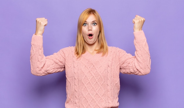 Mujer bonita pelirroja celebrando un éxito increíble como un ganador, luciendo emocionada y feliz diciendo ¡toma eso!