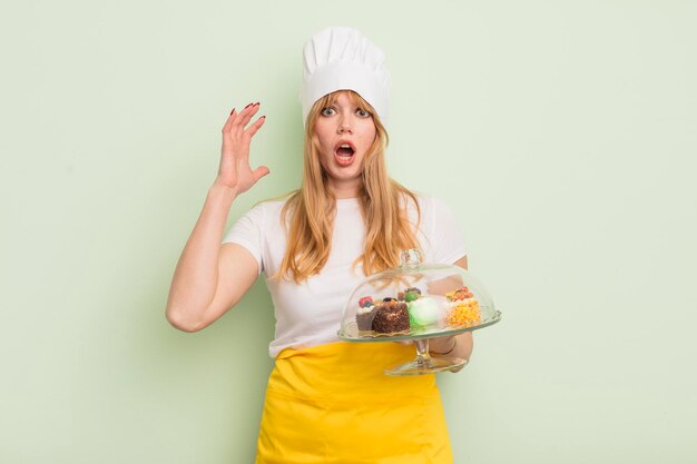 Mujer bonita pelirroja gritando con las manos en el aire. concepto de pasteles caseros