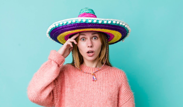 Mujer bonita pelirroja que parece feliz, asombrada y sorprendida, concepto de sombrero mexicano