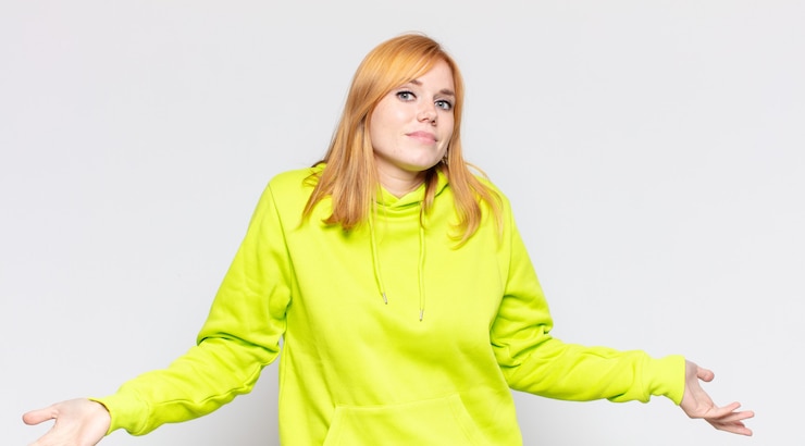 Foto mujer bonita pelirroja que se siente despistada y confundida, sin idea, absolutamente desconcertada con una mirada tonta o tonta