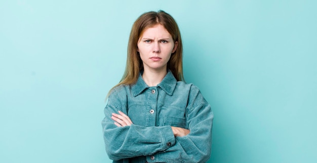 Mujer bonita pelirroja que se siente disgustada y decepcionada luciendo seria, molesta y enojada con los brazos cruzados