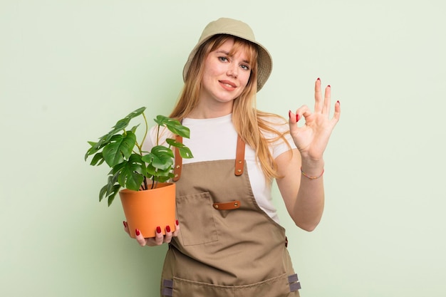 mujer bonita pelirroja que se siente feliz, mostrando aprobación con un gesto bien. concepto de jardinero