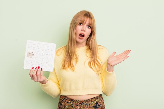 Mujer bonita pelirroja que se siente feliz sorprendida al darse cuenta de una solución o idea concepto de rompecabezas incompleto