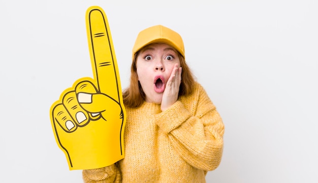 Mujer bonita pelirroja que se siente sorprendida y asustada concepto de ventilador de mano número uno