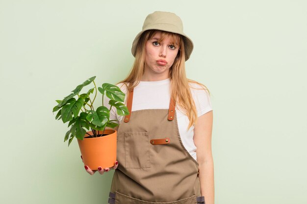 Mujer bonita pelirroja que se siente triste y quejumbrosa con una mirada infeliz y un concepto de jardinero llorando