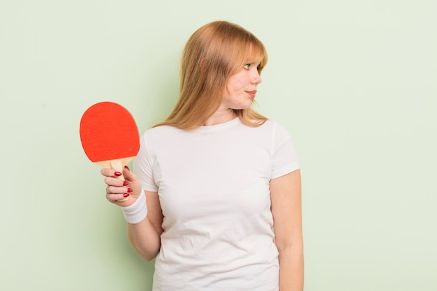 Mujer bonita pelirroja en la vista de perfil pensando, imaginando o soñando despierta. concepto de ping pong