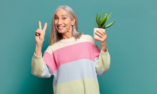 Mujer bonita de pelo gris con un cactus