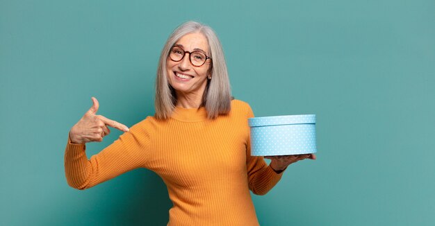 Mujer bonita de pelo gris con una caja de regalo