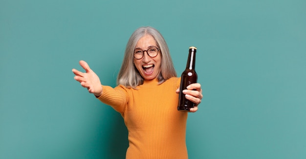 Mujer bonita de pelo gris tomando una cerveza