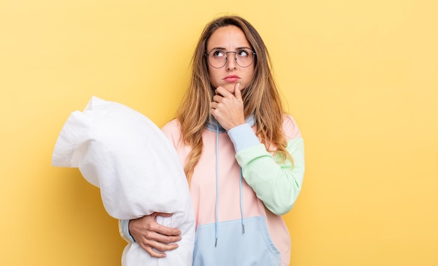 Mujer bonita pensando, sintiéndose dudosa y confundida. concepto de pijama