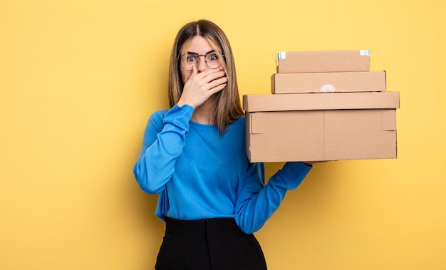 Mujer bonita que cubre la boca con las manos con un concepto de cajas de paquetes impactados