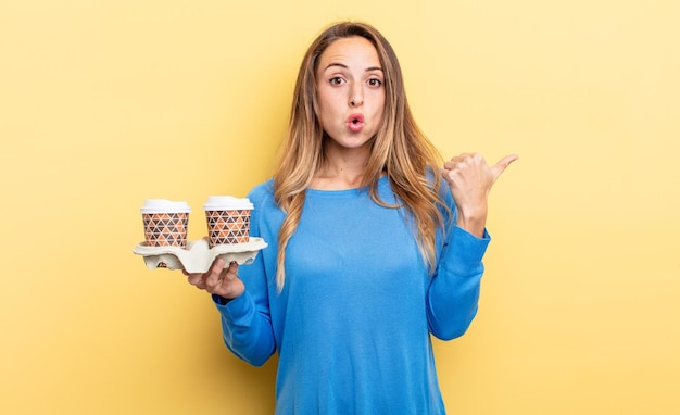 Mujer bonita que parece asombrada con incredulidad para llevar el concepto de café