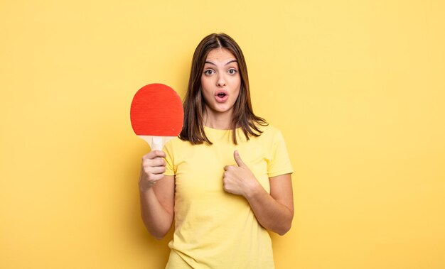 Mujer bonita que parece conmocionada y sorprendida con la boca abierta, apuntándose a sí misma. concepto de ping pong