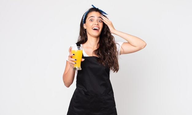 Mujer bonita que parece feliz, asombrada y sorprendida y sosteniendo un vaso de jugo de naranja