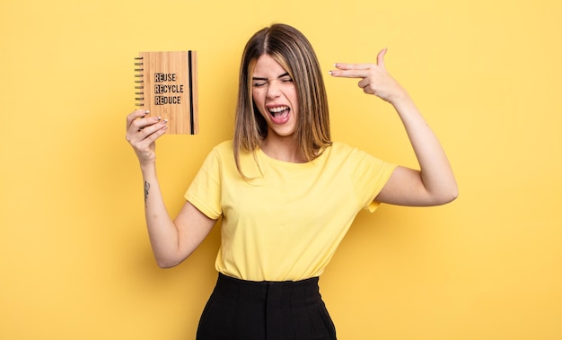 Mujer bonita que parece infeliz y estresada, gesto de suicidio haciendo señas de armas. concepto de reciclaje