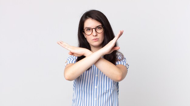 Mujer bonita que parece molesta y harta de tu actitud, ¡diciendo basta! manos cruzadas al frente, diciéndote que te detengas