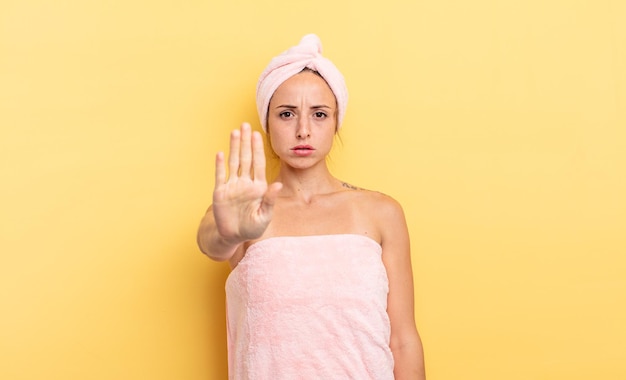 mujer bonita que parece seria mostrando la palma abierta haciendo un gesto de parada. concepto de ducha y belleza