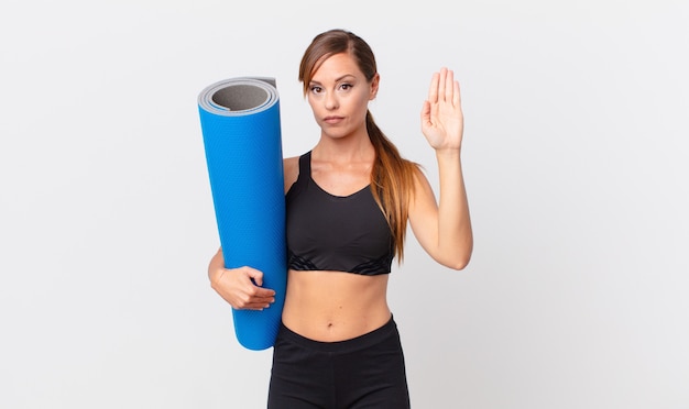 Mujer bonita que parece seria que muestra la palma abierta que hace el gesto de la parada. concepto de yoga