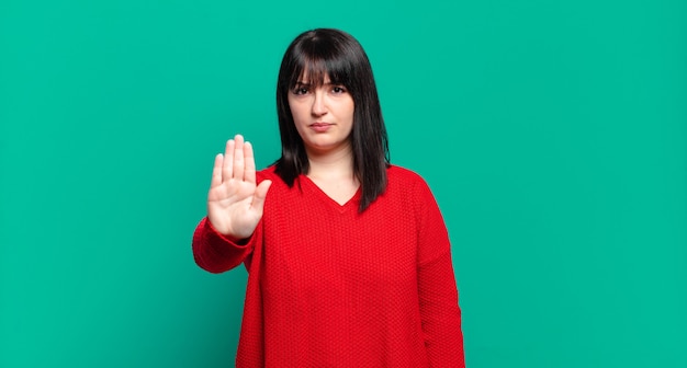 Mujer bonita que parece seria, severa, disgustada y enojada mostrando la palma abierta haciendo gesto de parada