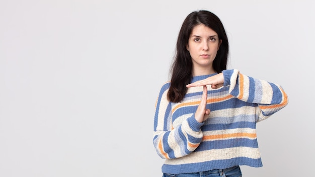 Mujer bonita que parece seria, severa, enojada y disgustada, haciendo el signo de tiempo de espera