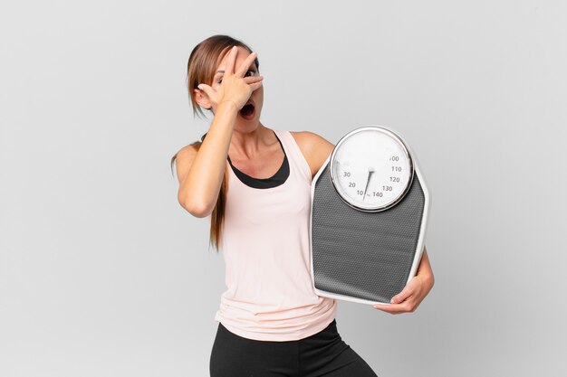 mujer bonita que parece sorprendida, asustada o aterrorizada, cubriéndose el rostro con la mano. concepto de dieta