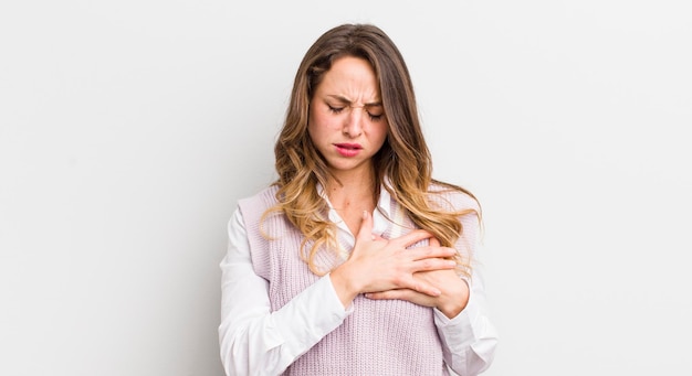 Mujer bonita que parece triste, herida y con el corazón roto sosteniendo ambas manos cerca del corazón llorando y sintiéndose deprimida