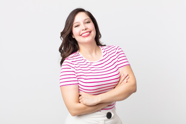 Mujer bonita que parece una triunfadora feliz, orgullosa y satisfecha sonriendo con los brazos cruzados