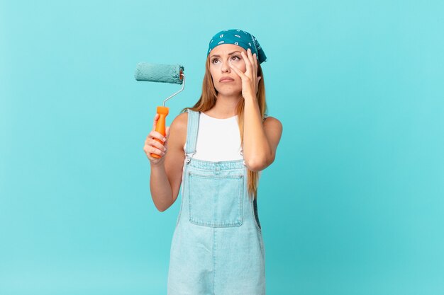 Mujer bonita que se siente aburrida, frustrada y somnolienta después de una pintura tediosa de la pared de una nueva casa