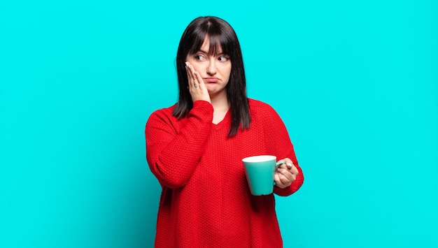 Mujer bonita que se siente aburrida, frustrada y con sueño después de una tarea tediosa, aburrida y tediosa, sosteniendo la cara con la mano