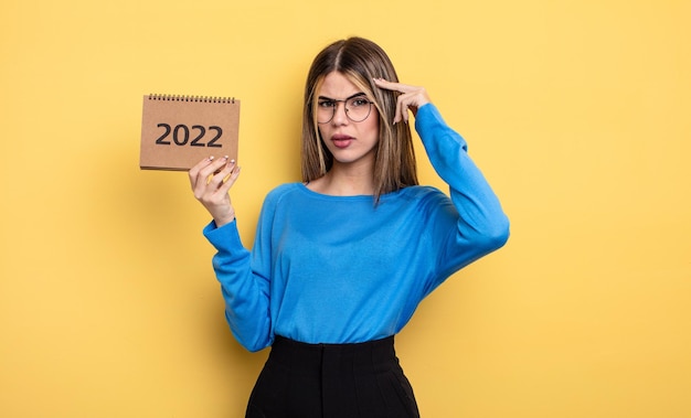 Mujer bonita que se siente confundida y desconcertada, mostrando que estás loca. concepto de calendario 2022