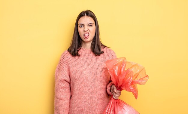 Mujer bonita que se siente disgustada e irritada y con la lengua fuera. concepto de bolsa de basura