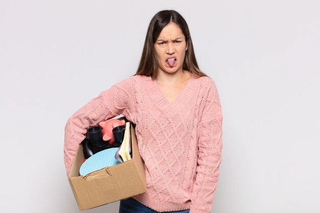 Mujer bonita que se siente disgustada e irritada, que saca la lengua, que no le gusta algo desagradable y asqueroso