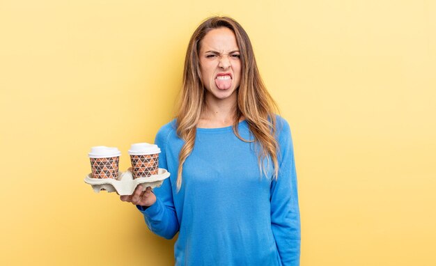 Mujer bonita que se siente disgustada e irritada y saca la lengua para llevar el concepto de café